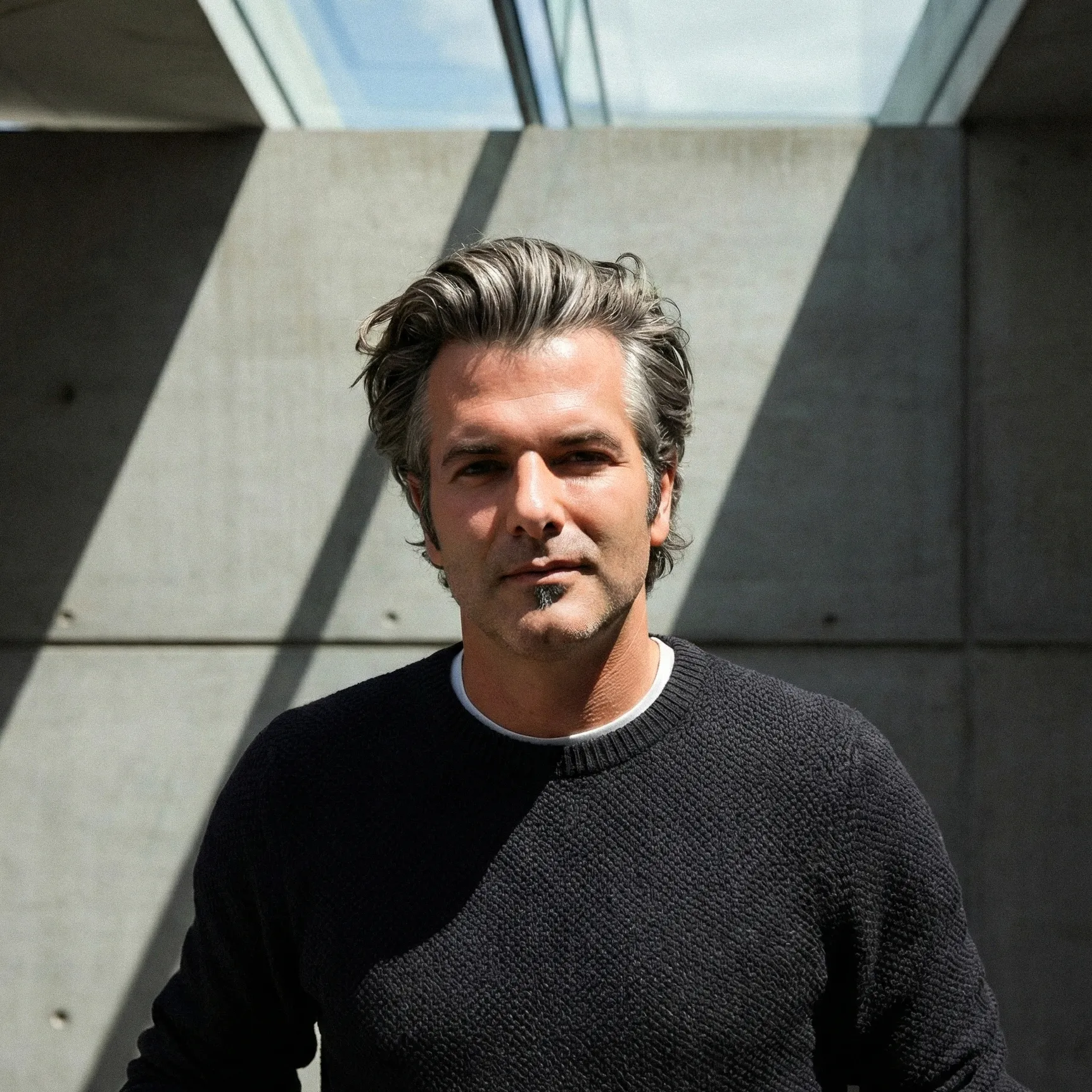 Florian Berger, Gründer von Berger+Team, blickt direkt in die Kamera vor einer modernen Betonwand mit markantem Schattenwurf.